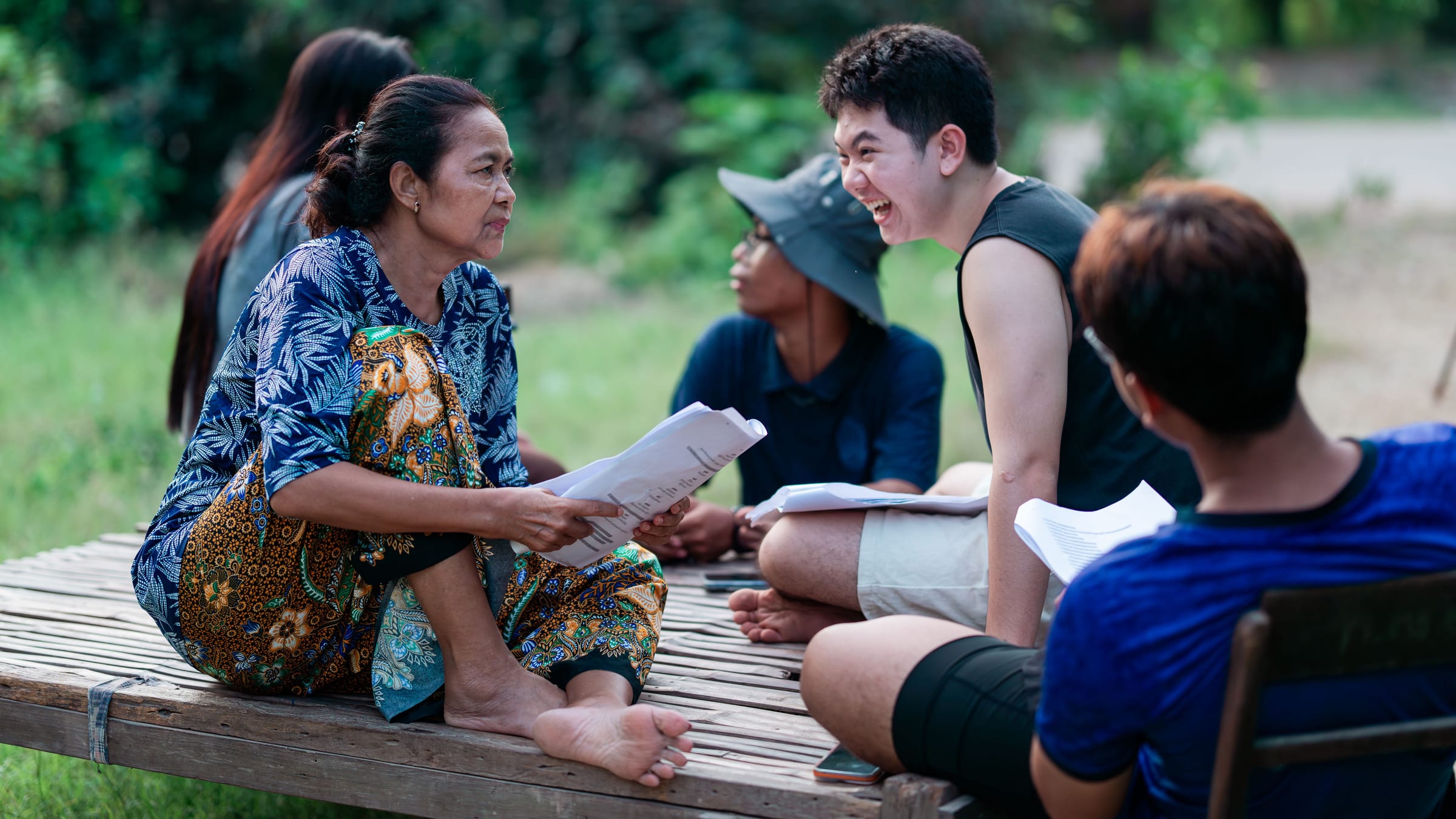 A small group sitting outdoors with papers, working through a session together.